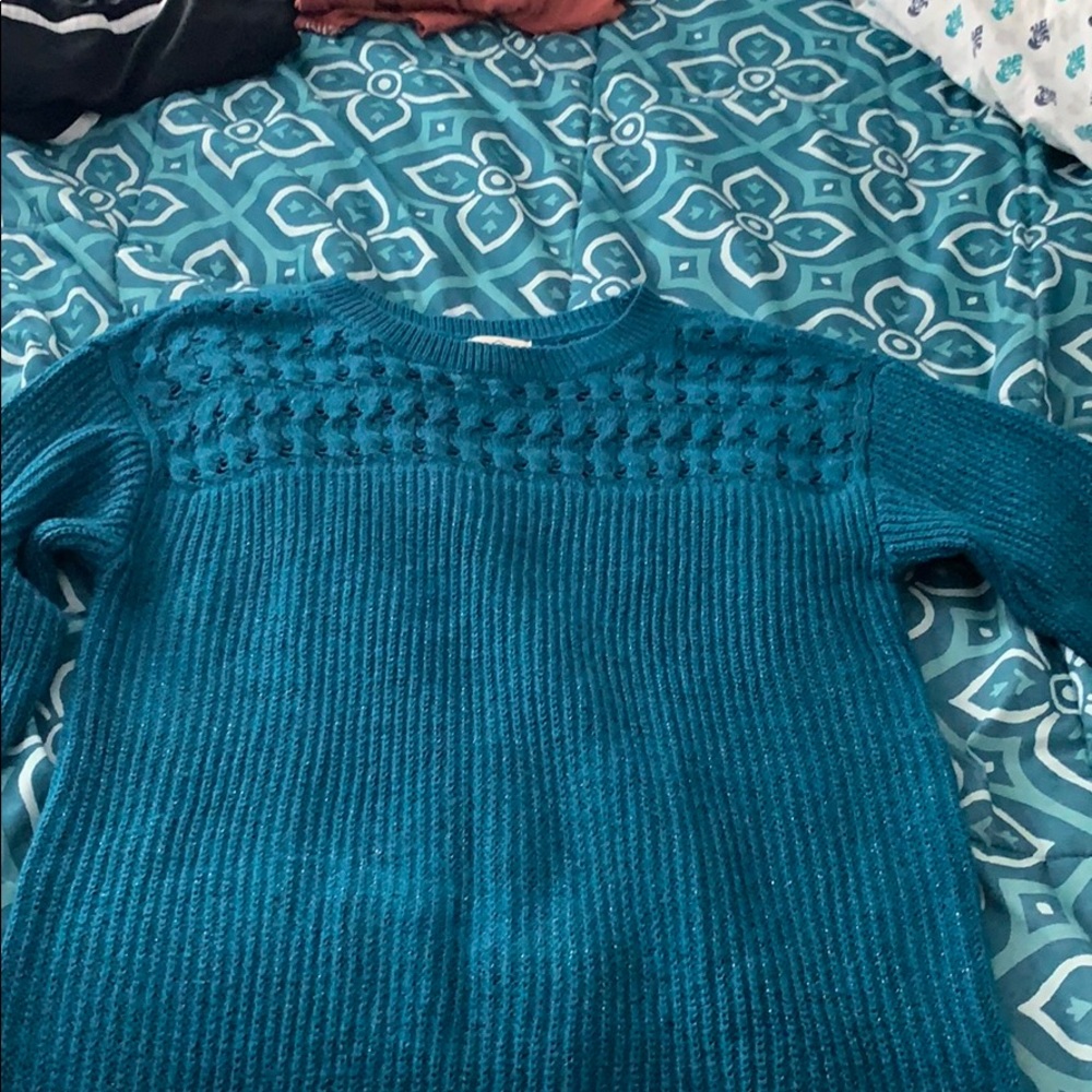 A sparkly teal sweater and a white sparkly sweater